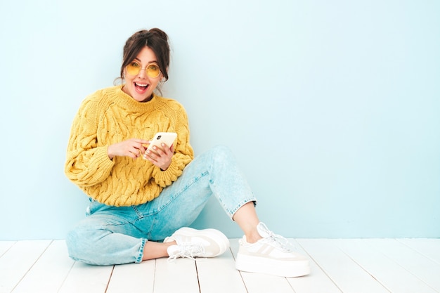 Young beautiful smiling female in trendy summer yellow hipster sweater and jeans