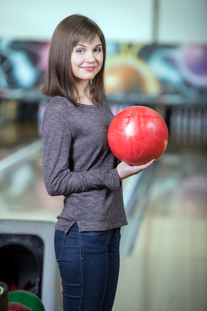 Young beautiful smiling girl playing bowling.