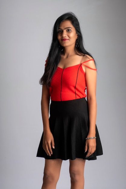 Young beautiful smiling girl in red and black outfit posing on grey background.