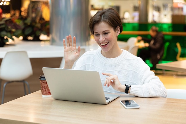 Young beautiful smiling happy brunette woman wearing white sweatshirt sitting at a shopping center