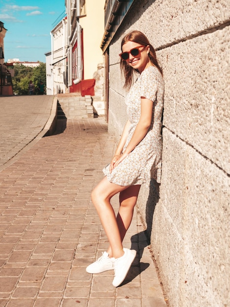 Young beautiful smiling hipster woman in trendy summer clothes Sexy carefree woman posing on the street background at sunset Positive model outdoors Cheerful and happy in sunglasses