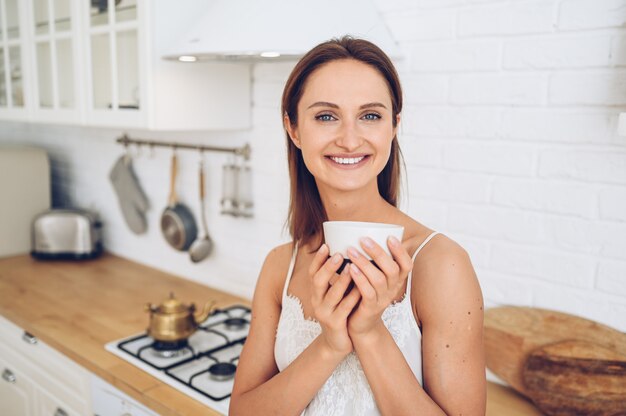 Young beautiful smiling woman drinking morning coffee.