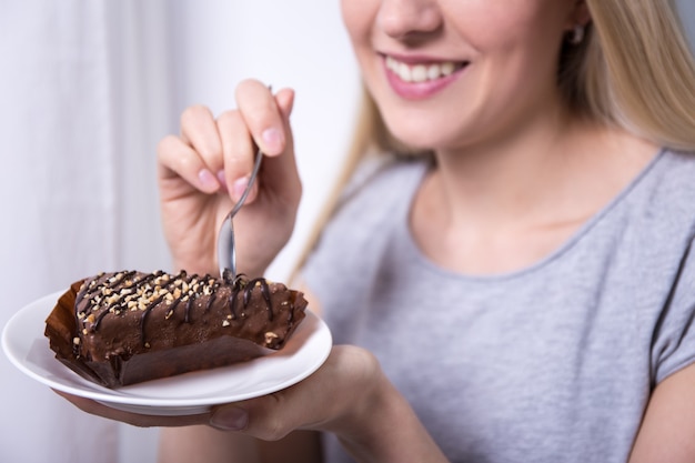 家でチョコレートケーキを食べる若い美しい笑顔の女性