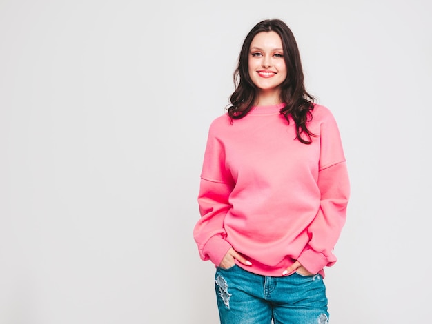 Young beautiful smiling woman in trendy jeans and sweater clothes Woman posing in studio