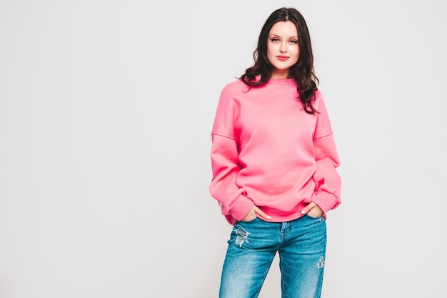 Young beautiful smiling woman in trendy jeans and sweater clothes Woman posing in studio