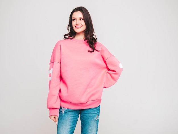 Young beautiful smiling woman in trendy jeans and sweater clothes Woman posing in studio
