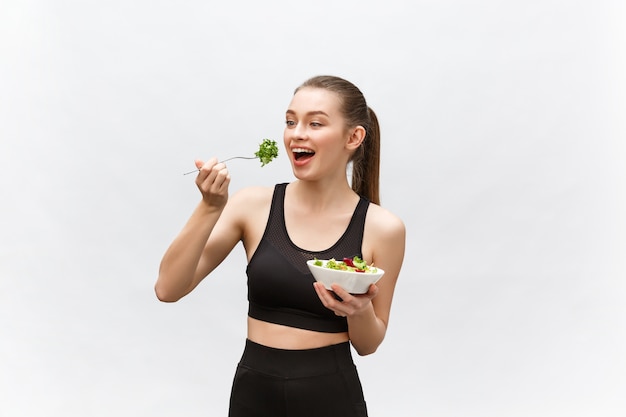 Young beautiful sport woman eating salad  