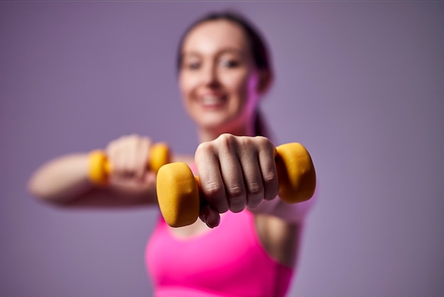 Young beautiful sports girl in leggings and a top does exercises with dumbbells. Healthy lifestyle.