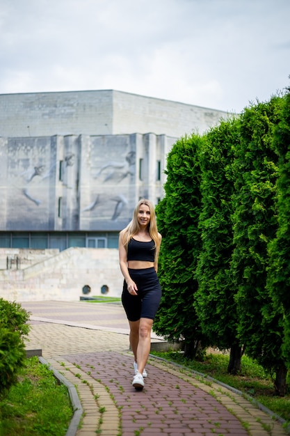 Young beautiful sporty blonde woman in a black T-shirt and in black tight sports shorts