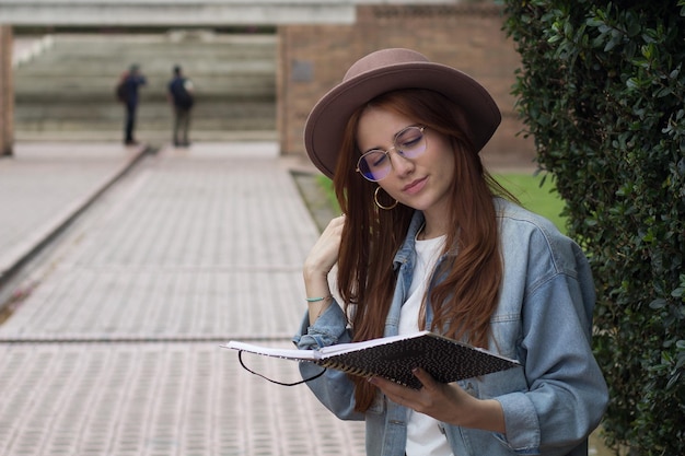 young beautiful student reading a book in a park in a university library