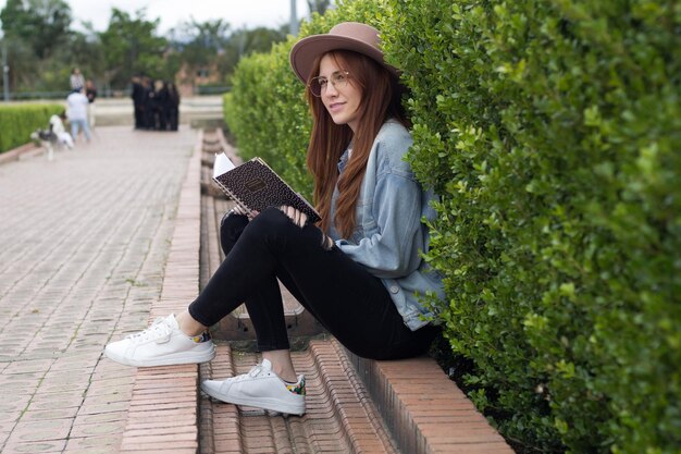 young beautiful student reading a book in a park in a university library