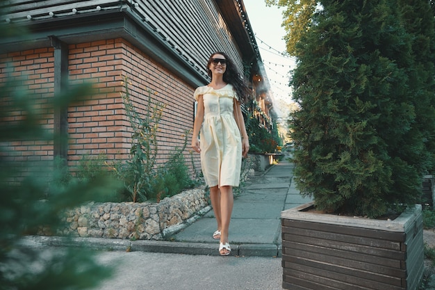 Young beautiful stylish woman in sunglasses walking on a summer dress