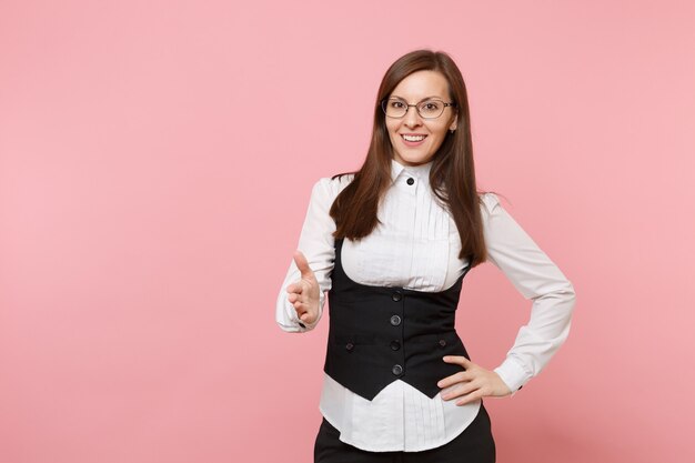 Young beautiful successful business woman in suit and glasses giving hand for handshake isolated on pastel pink background. Lady boss. Achievement career wealth concept. Copy space for advertisement.