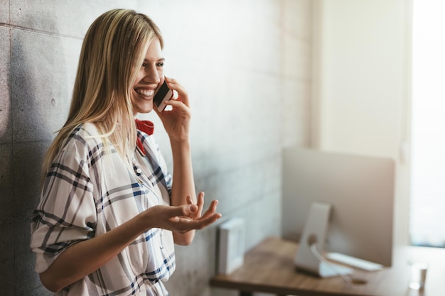 Foto giovane bella imprenditrice di successo che parla su uno smart phone nel suo ufficio.