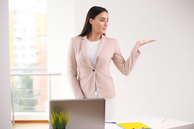 Young beautiful tanned woman presenting your product, over white background