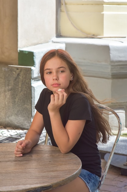 Giovane bella ragazza teenager che mangia caramelle al cocco in terrazza