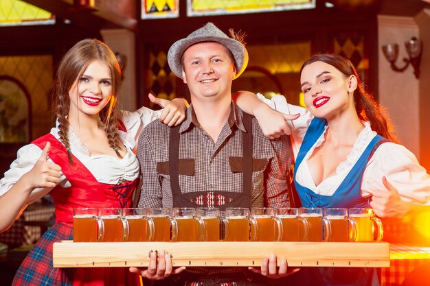 Young beautiful waiters in national costumes at the Oktoberfest party with a huge beer tray.