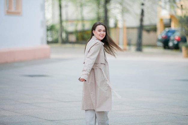 Young beautiful woman 19 years old in stylish clothes Model with dark hair in casual clothes walks through the spring blooming city Warm