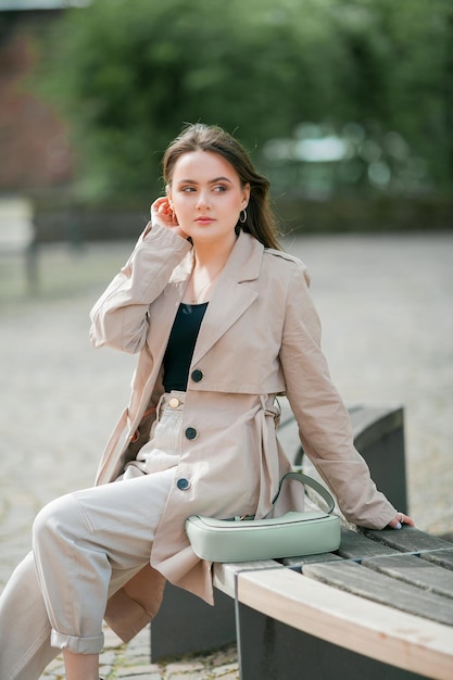 Young beautiful woman 19 years old in stylish clothes Model with dark hair in casual clothes walks through the spring blooming city Warm