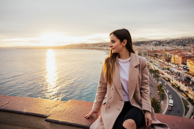 Giovane bella donna ammirando la vista panoramica della strada europea a nizza, in francia sul tramonto.