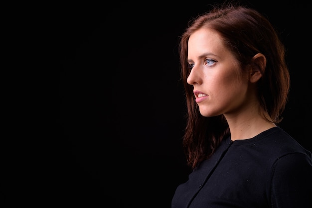 Photo young beautiful woman against black wall