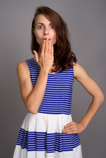 灰色の壁に対して若い美しい女性