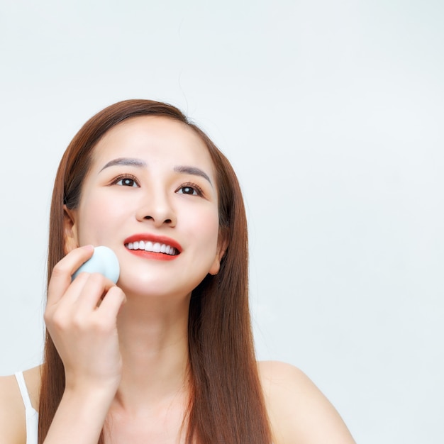 Photo young beautiful woman applying cosmetic with sponge