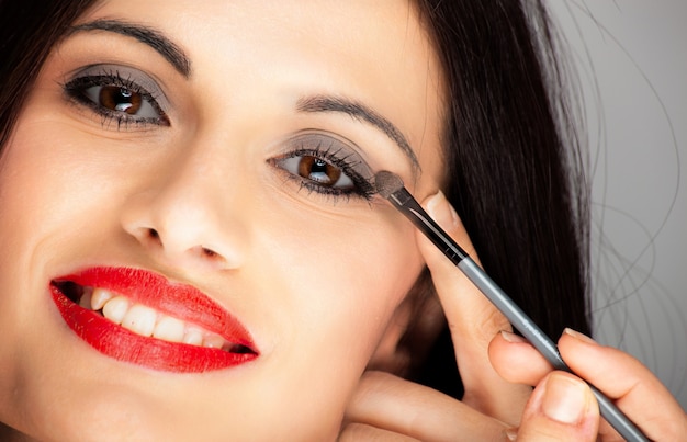 Young beautiful woman applying eyeliner on eyelid with pencil