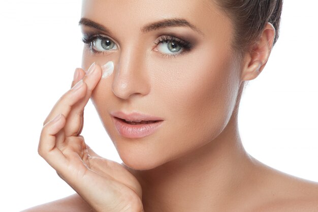 Young and beautiful woman applying moisturizing cream on her face