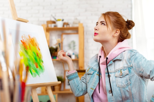 Young beautiful woman artist drawing abstract painting on an easel