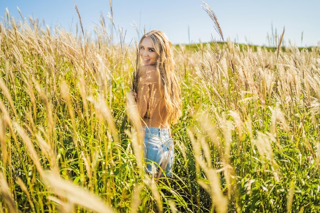 Young beautiful woman in autumn landscape with dry flowers, wheat spikes. Fashion autumn, winter. Sunny autumn, fashion photo