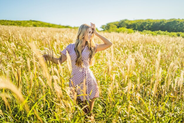 Young beautiful woman in autumn landscape with dry flowers wheat spikes Fashion autumn winter Sunny autumn fashion photo