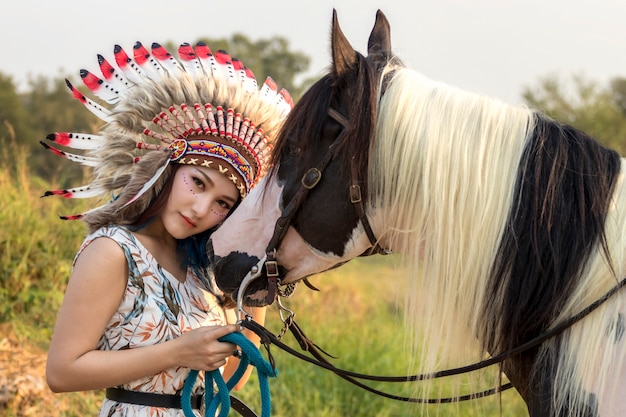 young beautiful woman, beauty, ethnic tribal make-up, drawings on face, red lips, earrings, bohemian hippie style and horse.