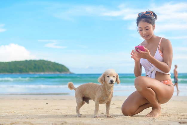 그녀의 강아지와 함께 비키니를 입고 해변에서 즐기고 휴식을 취하는 젊은 아름다운 여자