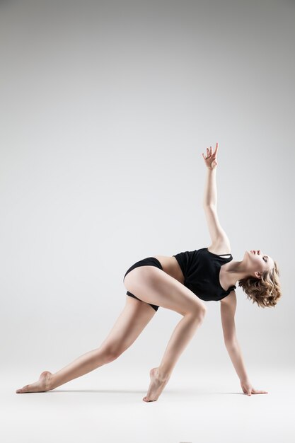 Young beautiful woman in black T-shirt and black shorts dancing , studio series