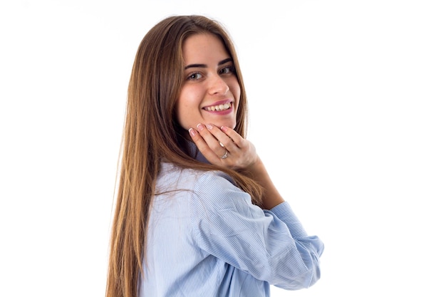 Молодая красивая женщина в синей рубашке с длинными волосами смотрит вниз на белом фоне в студии