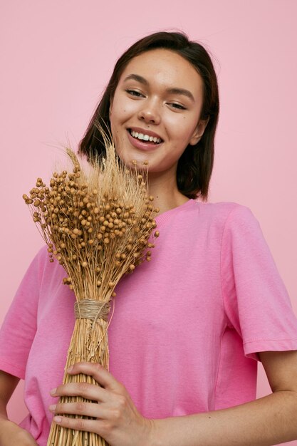 Young beautiful woman a bouquet of dried flowers pink tshirt
isolated background