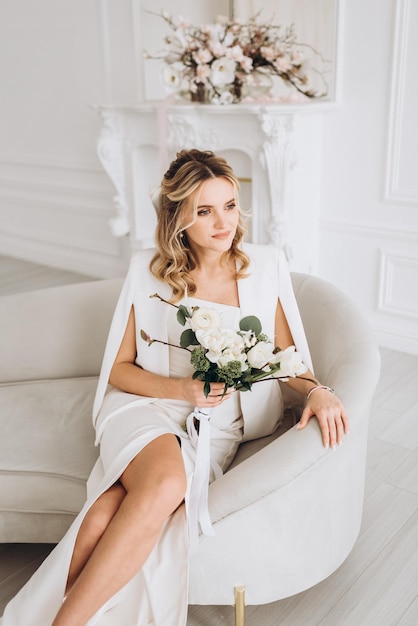 young beautiful woman bride in a wedding dress with a bouquet of flowers in a bright interior