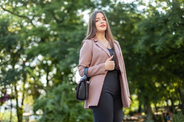 Young beautiful woman in business clothes showing thumb up in the park