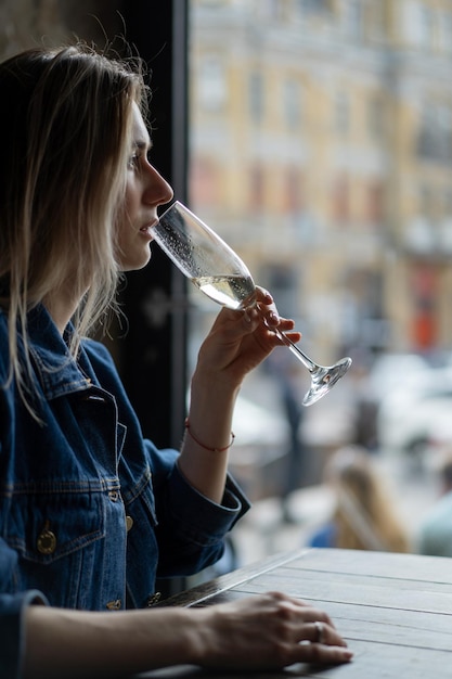 Giovane bella donna in un caffè, una donna che beve champagne in un caffè e parla.