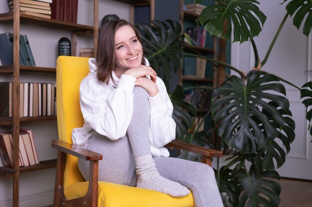 Young beautiful woman in casual clothes sitting on yellow couch in modern interior