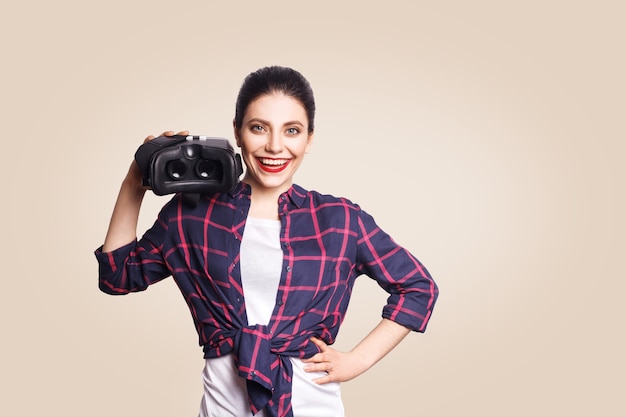 Young beautiful woman in casual style with virtual reality headset on beige background. studio shot. .