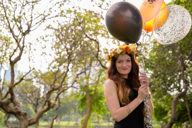 Giovane bella donna che celebra laurea al parco