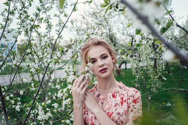 桜の咲く庭にいる若い美女女性の顔が白い花と桜の枝に隠されている春の自然甘い香り咲く春の桜甘い香りの香り