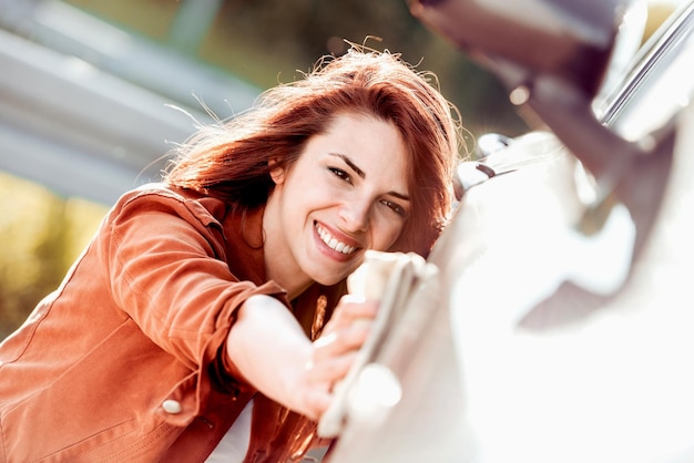 Foto giovane bella donna che pulisce la sua auto all'autolavaggio