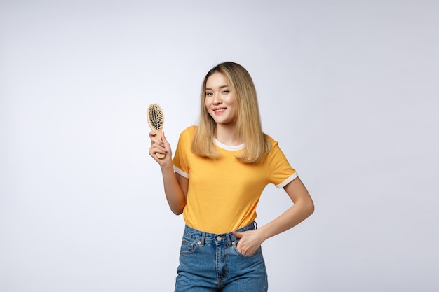 Photo young beautiful woman combing her hair