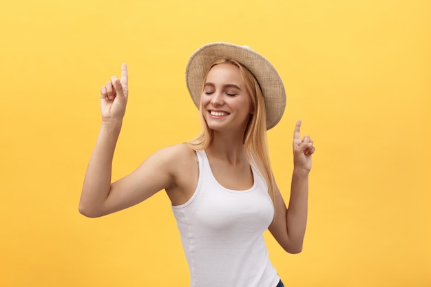 Young beautiful woman dancing in studio isolated on yellow background