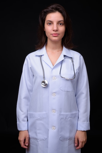 young beautiful woman doctor against black wall