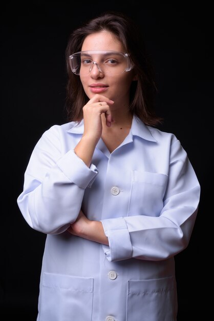 young beautiful woman doctor against black wall