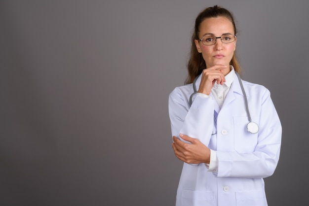 Young beautiful woman doctor against gray background